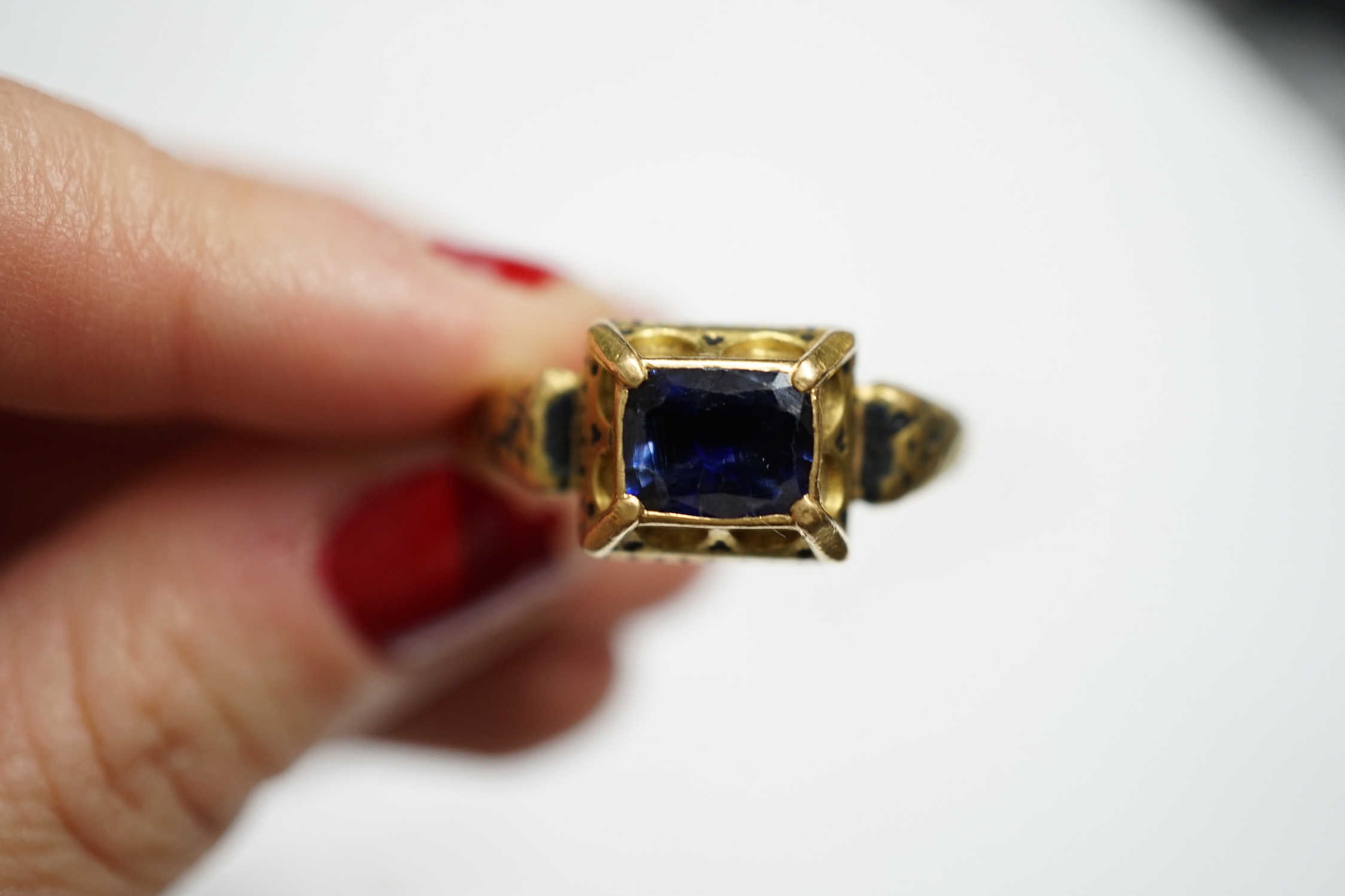 An antique high carat gold, black enamel and collet set cushion cut sapphire set 'poison' ring